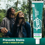 Lifestyle image of smiling couple in a forest with a vertical tube of Tom's Whiten+ Deep Clean toothpaste and 'Prevents Stains' claim