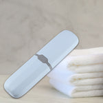Light blue toothbrush travel case placed diagonally on a bathroom counter with folded towels