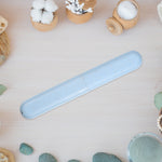 Speckled blue toothbrush travel case placed flat on a light wood surface with cotton and cosmetic props