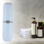 Vertical light blue toothbrush case in a styled bathroom scene with towels and pump bottles on a counter