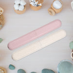 Pink and beige speckled toothbrush travel cases placed on a wooden surface with spa-style props and small containers.
