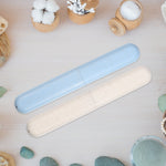 Speckled blue and beige toothbrush travel cases displayed on a wooden surface with bathroom accessories