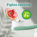 Close-up of a toothbrush with a dollop of toothpaste and watermelon character graphic labeled ages 2+