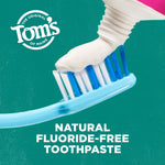 Toothpaste being squeezed onto a blue toothbrush against a teal background with the Tom's of Maine logo and 'natural fluoride-free toothpaste' text.