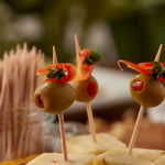 Close-up of appetizers skewered with wooden toothpicks showing olives and cheese on a blurred background