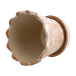 Top-down view into a scalloped ceramic planter showing cream interior and textured terracotta exterior