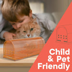 Close-up lifestyle image of translucent brown humane mouse trap on a table with blurred child and cat in background