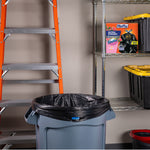 Garage scene with a gray trash can lined with a black Hefty trash bag and a Hefty Fabuloso watermelon box on a metal shelf