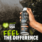 Hand holding a TREK insect repellent spray can while a fine mist sprays; 'Proudly made in the USA' badge and 'Feel the difference' text visible.