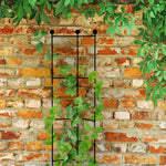Black metal trellis mounted against a rustic brick wall with green climbing vine threaded through its vertical and horizontal supports.