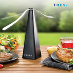 Treva black bug fan displayed on a wooden table in an outdoor dining scene with salad and grilled food.