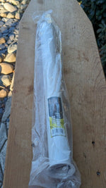 White PVC sand spike in clear plastic packaging showing a yellow product label, photographed on a wooden board