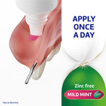 Close-up of a tube dispensing pink adhesive onto the underside of a denture with text ‘APPLY ONCE A DAY’