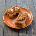 Two baked harvest-shaped mini loaves on an orange plate highlighting leaf and acorn shapes