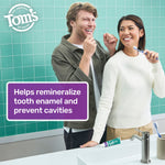 Two people smiling in a bathroom setting with a Tom's of Maine toothpaste tube on the counter and a purple panel highlighting enamel remineralization benefits.