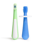 Two toddler training toothbrushes standing upright - one green soft-bristle brush and one blue silicone 360° brush