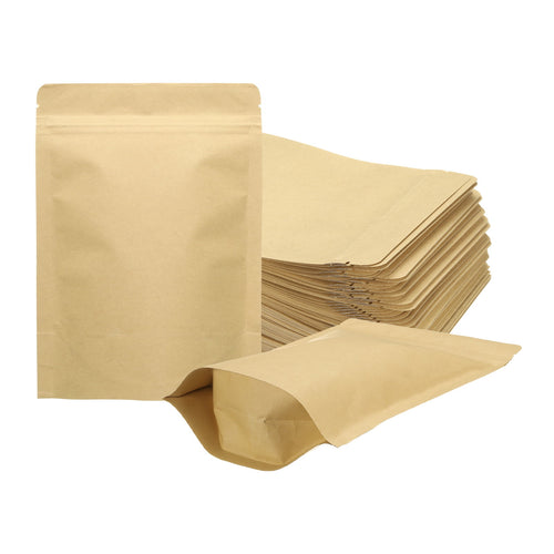 Stack of flat kraft paper stand-up sealable bags with one open and one filled-looking bag on a white background