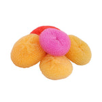 Small pile of round orange and pink mesh dish scrubbers arranged on white