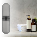 Vertical gray travel toothbrush case staged on a bathroom counter alongside towels and pump bottles