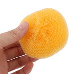 Hand holding a yellow round plastic mesh scouring pad against a white background