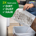 Hand holding a used Swiffer dry cloth over a trash can showing trapped dirt and hair with '2X Trap+Lock' callout