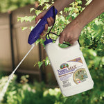 Photo of hands holding a Neem MAX jug and spraying wand, applying a fine spray over garden foliage