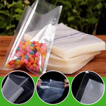 Clear vacuum sealer bags displayed with jelly beans in one bag and stacked unsealed bag pads on a wooden surface