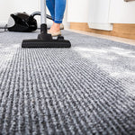 Low-angle view of a vacuum cleaning a textured gray carpet with white powder residue visible