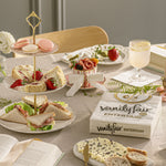 Styled table setting with Vanity Fair Entertain napkin pack placed beside tiered tray of sandwiches and desserts