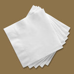 Stacked white Vanity Fair beverage napkins fanned on a brown background showing texture and square shape