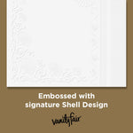 Close-up of an embossed white napkin corner with shell design and text noting the signature shell embossing