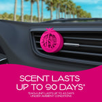 Pink circular California Scents vent clip attached to a car air vent with palm trees visible through the windshield