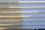 Close-up of vinyl siding showing a cleaned right side and a stained left side to illustrate cleaning results.