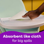 Hand wiping a highchair tray with a Viva paper towel, purple banner reading 'Absorbent like cloth' at bottom.