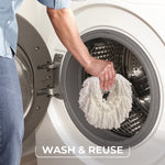 Hand placing a white microfiber mop refill into a front-loading washing machine drum with caption wash & reuse