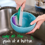 Hands washing a blue bowl with a Scotch-Brite soap-control dishwand showing soap dispensed at the push of a button