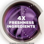 Close-up of a washing machine door with purple laundry and text overlay reading “4X FRESHNESS INGREDIENTS”