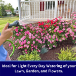 Lifestyle image of a person watering pink flowering bushes with a green hose and spray nozzle, water visible