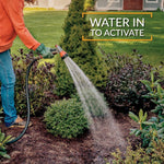 Outdoor scene of a person watering a garden bed with a hose, overlaid text reading 'WATER IN TO ACTIVATE'.