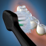 Illustration of a black Waterpik brush head brushing teeth with simulated bristle motion and cleaning particles.