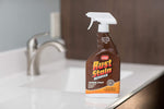 Whink Rust Stain Remover foaming spray bottle placed on a bathroom countertop near a sink and faucet.