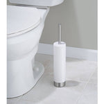 White cylindrical toilet brush holder with brushed stainless steel handle and base positioned by a toilet