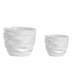 Studio shot of two white ceramic pots with wave-like textured sides against a white background.