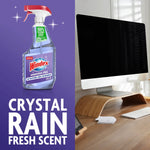 Windex ammonia-free bottle on purple background next to a desktop computer, with large 'Crystal Rain Fresh Scent' text