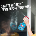 Hand using a spray trigger on a Windex bottle spraying solution onto a glass door with headline 'Starts working even before you wipe'.