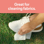 Lifestyle photo of a person wiping a white sneaker with a cleaning wipe on grass under headline great for cleaning fabrics