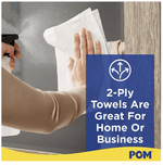 Person wiping a surface with a white paper towel, blue overlay text states '2-Ply Towels Are Great For Home Or Business' with POM logo.
