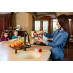 Woman in a kitchen demonstrating the red fruit fly trap on the counter while children sit at the island