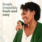Smiling woman holding a green blanket to her face with text about smelling irresistibly fresh and cozy