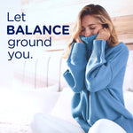 Woman in a blue sweater smiling and burying her face into the fabric next to large text 'Let BALANCE ground you.'